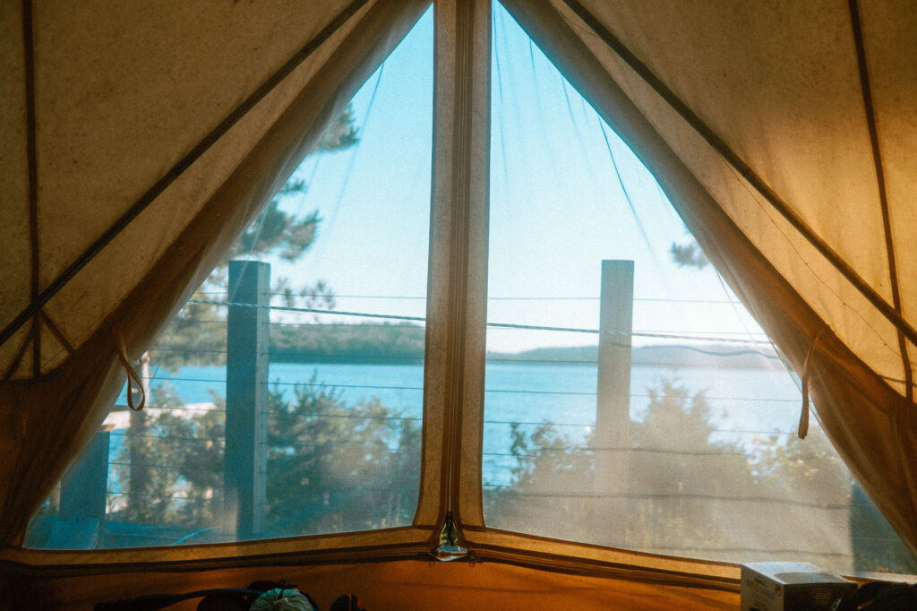 Views of Murray Lake through the vented screen tent doors from inside the glamping tent at Pine Falls Lodge, located in the Greater Sudbury Area (Markstay-Warren)