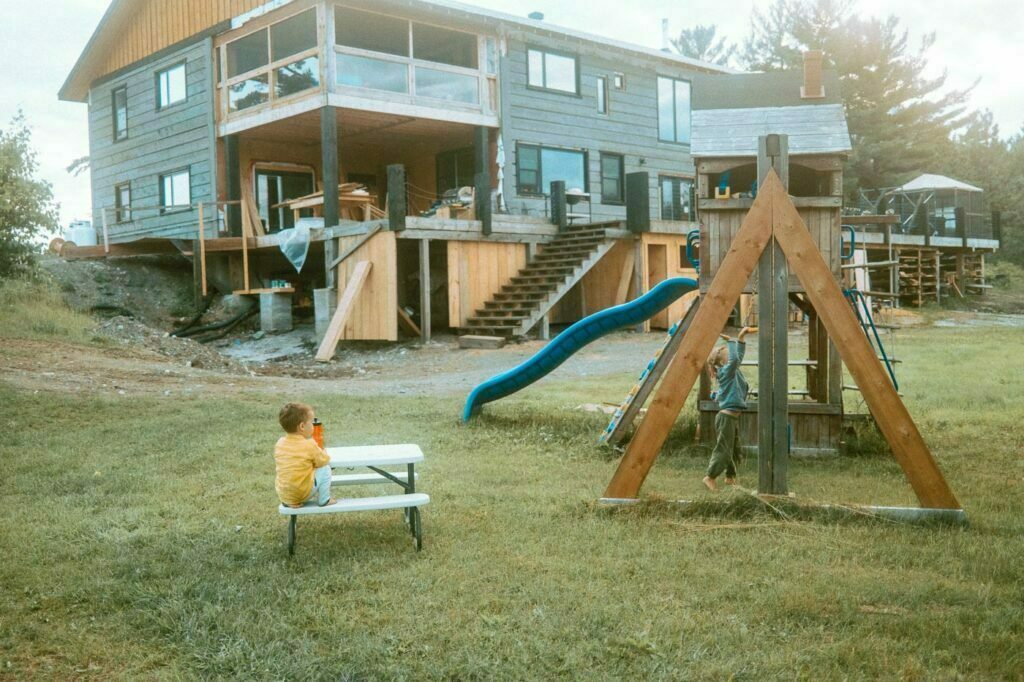 Rear view of the under renovation Pine Falls Lodge with current owner's children playing on the play structure nearby
