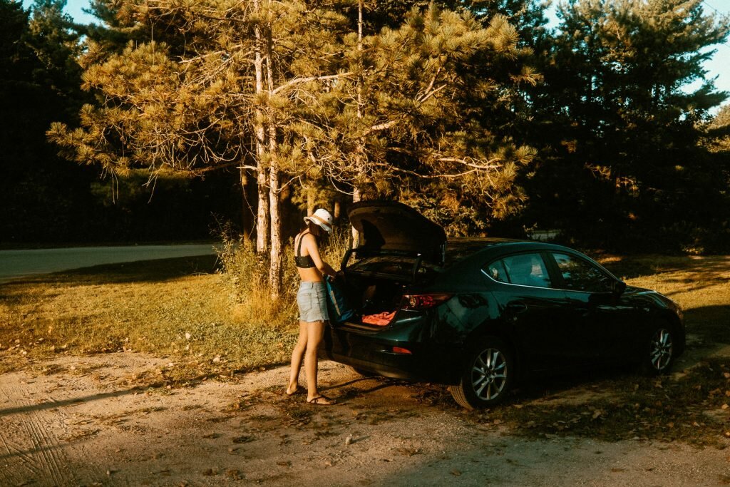 Woman packing items into a trunk of a car parked at Long Point Provincial Park's West End - near the dog beach access area