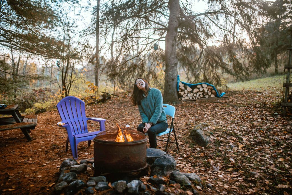 Maria from SYDE Road roasting a marhsmallow on top of a fire cauldron at the rustic cozy cabin near Minden, Ontario - Hipcamp Canada Listing