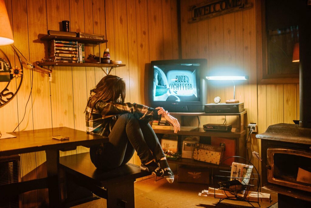 Maria from SYDE Road, watching Toy Story on a vintage CRT TV in the evening at the rustic cozy cabin in Minden, Ontario - Hipcamp Canada listing - 90s nostalgia
